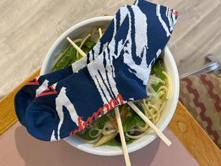 a pair of voltage socks laying over a bowl of ramen
