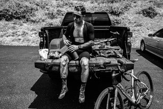 Johnny Collinson sitting in his truck bed drinking water in black and white