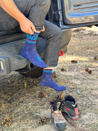 putting on voltage wool socks on a truck bed next to hiking shoes