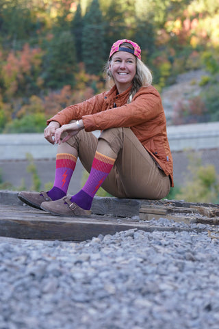 Shannon Finch sitting on a bridge wearing her Voltage stokeberry collection