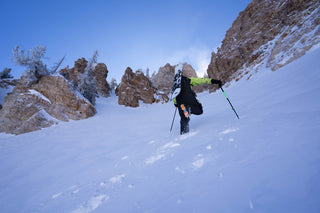 a man hiking up a snowy mountain in his snowboarding gear