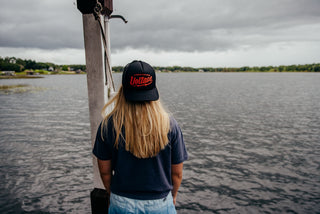 A girl looking out over a stormy lake wearing a backwards Voltage foam hat