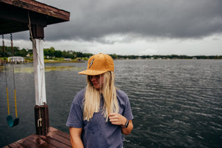 A girl standing by a cloudy lake wearing a wool Voltage hat