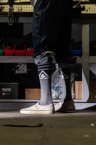 Legs of a guy in a ski shop wearing grey magic snow socks