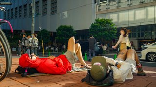 Two men laying down on the side of a busy street wearing Voltage hats 